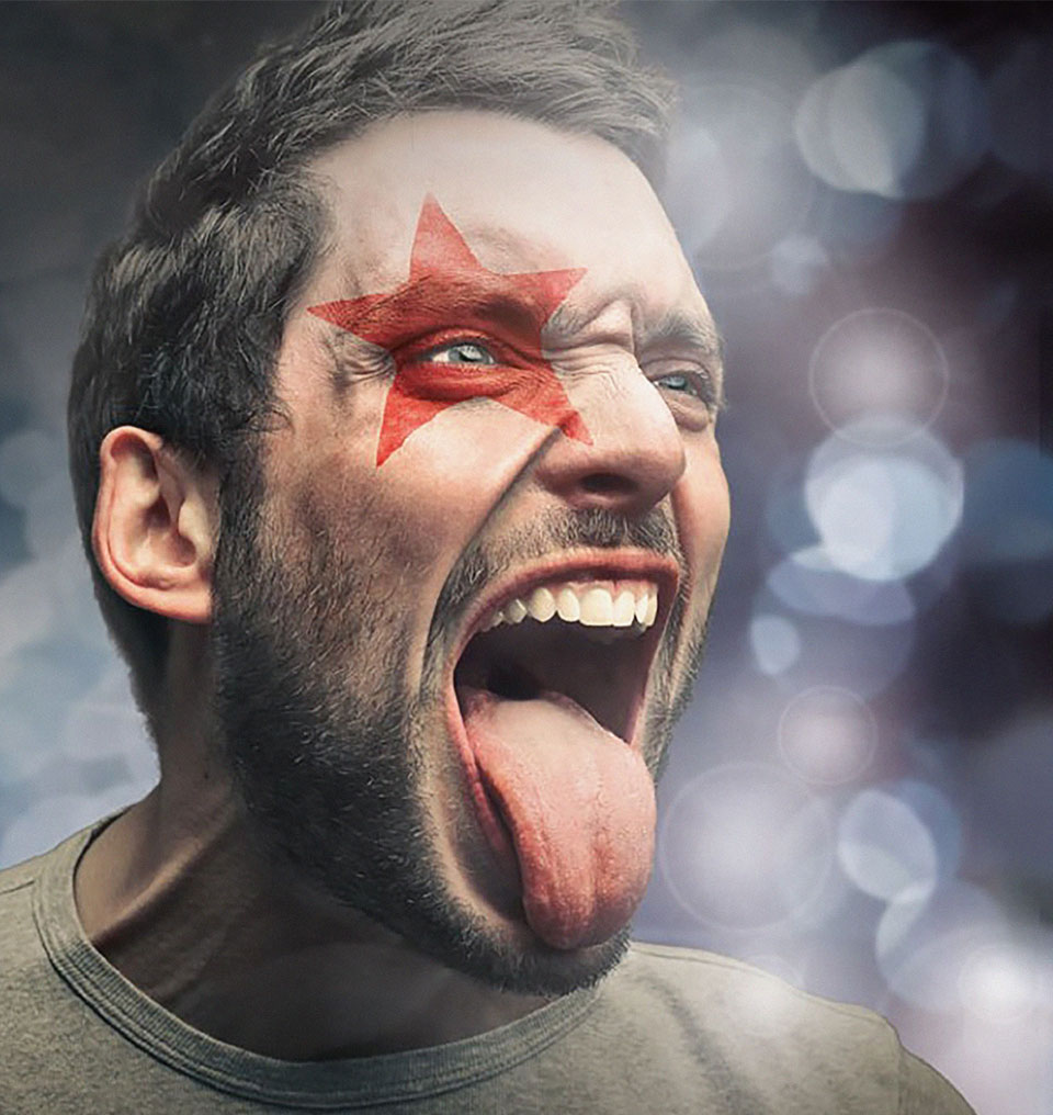 Mann mit gemaltem Starmix-Stern am Auge streckt Zunge raus